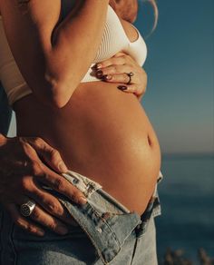 a man and woman standing next to each other with their hands on their stomachs