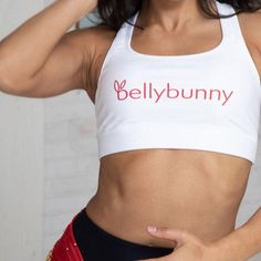 Our signature white sports bra with red logo boasts a scoop neck and a racerback for a secure fit. Constructed with a moisture-wicking fabric that stays dry during low to moderate intensity activities, it's the perfect choice for dance or gym classes. Team it with Bellybunny leggings and hoodie for a super cute and comfortable look! White Sports Bra With Built-in Padding, White Yoga Sports Bra With Built-in Padding, White Sports Bra With Built-in Padding For Workout, White Activewear With Built-in Padding For Gym, Fitted White Activewear With Built-in Padding, Fitted White Sports Bra With Built-in Bra, Functional White Sports Bra For Workout, Functional White Activewear For Workout, White Activewear With Built-in Bra For Training