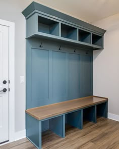 an empty bench in the corner of a room next to a white door and wooden floor