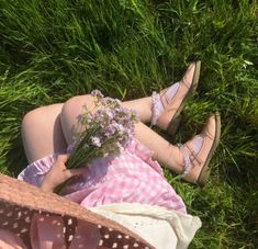 a woman laying on the grass with flowers in her hand and wearing high heeled shoes