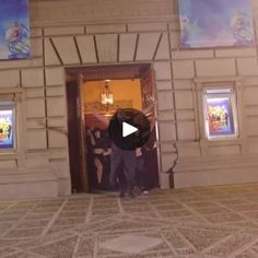 two men standing in front of a building with posters on the walls and doors behind them