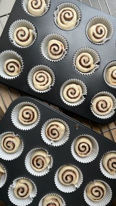 two pans filled with cinnamon rolls sitting on top of a metal rack