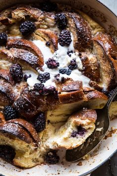 a pan filled with bread and berries on top of a table