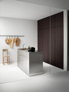 a modern kitchen with white walls and wooden cabinets, along with hanging utensils