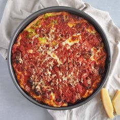 a pizza in a pan with cheese and sauce on the top, next to a piece of butter