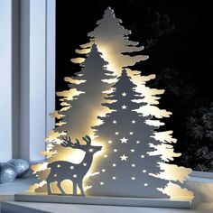 a white christmas tree with lights in the shape of trees and stars on it, next to a window sill