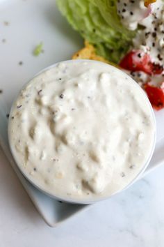 a white plate topped with lettuce covered in ranch dressing next to a salad