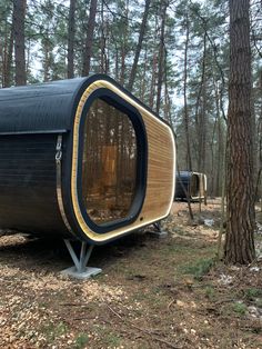 a small black and yellow house in the woods with trees around it's sides