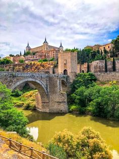 an old stone bridge over a river in front of a castle