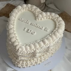 a white heart shaped cake on top of a table