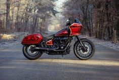 a red and black motorcycle parked on the side of a road in front of trees