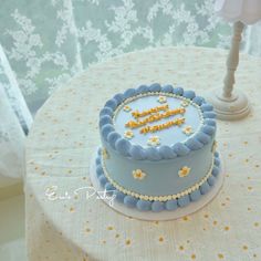 a blue cake sitting on top of a table next to a white light pole and window