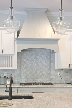 an image of a kitchen setting with white cabinets and marble backsplashes on the island