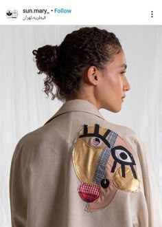 a woman wearing a jacket with an image of a face on the back of it