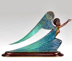 a figurine of a woman holding a seashell in her hand and flying through the air