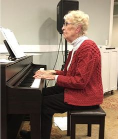 an older woman sitting at a piano in a room