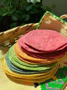 a basket filled with lots of different colored flatbreads on top of a table