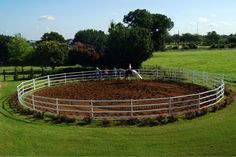 people standing around a fenced in horse pen