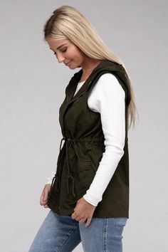 A versatile fashion piece that seamlessly blends style and utility. This vest boasts a convenient zipper and snap-button closure, ensuring ease of wear, while the adjustable drawstring waist provides a personalized, flattering fit. With practical pockets, it's a fashionable yet functional addition to any outfit, making it perfect for both casual and statement looks. Model is wearing a SmallModel SpecsHeight: 5'8"Bust: 34D Waist: 24"Hips: 37"*Color may vary slightly due to monitor resolutionMade Hooded Outdoor Vest For Spring, Casual Outerwear With Drawstring For Outdoor Activities, Urban Vest With Pockets For Fall, Urban Style Vest With Pockets For Fall, Urban Fall Vest With Pockets, Urban Style Fall Vest With Pockets, Fall Streetwear Vest With Side Pockets, Urban Cotton Vest For Fall, Drawstring Outerwear For Fall Outdoor Activities