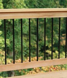 a wooden deck with black iron railings and trees in the backgroung