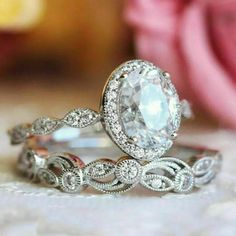 two wedding rings with an oval diamond in the center