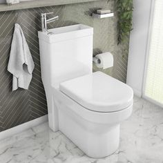 a white toilet sitting in a bathroom next to a wall mounted towel dispenser