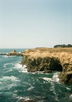 an ocean view with waves crashing on the rocks