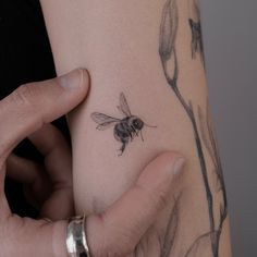 a woman's arm with a bee tattoo on the left side of her arm