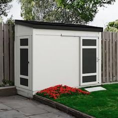 a small white shed sitting on top of a lush green field