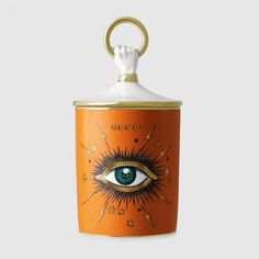 an orange canister with the eye painted on it and gold trimming around the top