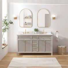 a white bathroom with two mirrors above the sinks and a rug on the floor next to it