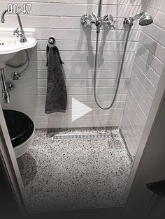 a walk in shower sitting next to a white sink and black counter top under a faucet