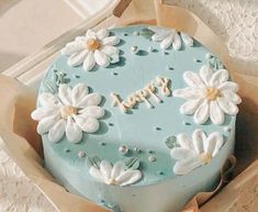 a blue cake with white flowers and the word happy written on it in frosting