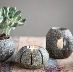 two rocks with candles in them sitting on a table next to a succulent plant