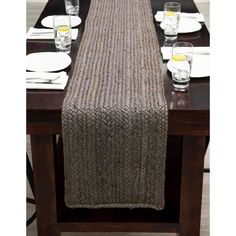 the table is set with place settings and glasses on it, along with a knitted runner