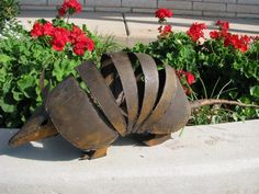 a metal object sitting on the ground next to flowers