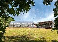 a group of people standing in front of a green house on top of a lush green field