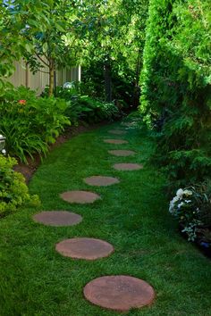 a garden path with stepping stones in the grass and trees around it, surrounded by greenery