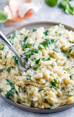 a plate full of pasta with spinach and parmesan cheese on the side