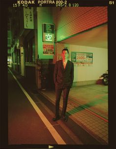 a man in a suit standing on the side walk