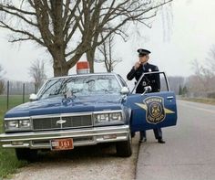 a police officer standing next to a blue car