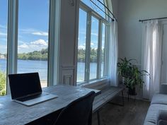 a laptop computer sitting on top of a wooden table in front of a large window