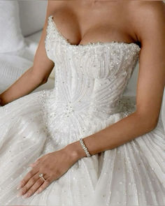 a woman in a wedding dress sitting on a bed with her hand on the pillow