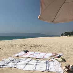 an umbrella and towels are laying on the beach