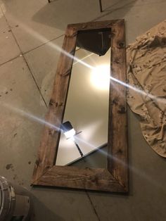 a mirror sitting on the floor next to a light fixture and a wall mounted fan