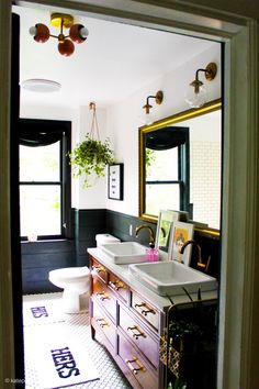 a bathroom with two sinks, mirrors and plants on the counter top in front of it