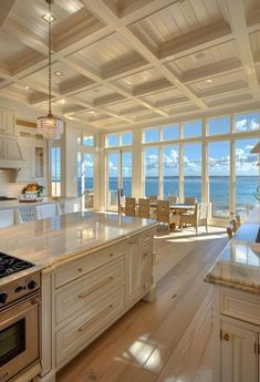 a kitchen with an island, stove and large window overlooking the ocean is pictured in this image