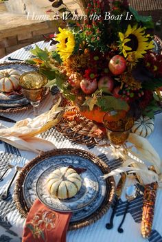 a table topped with plates and vases filled with autumn flowers next to pumpkins