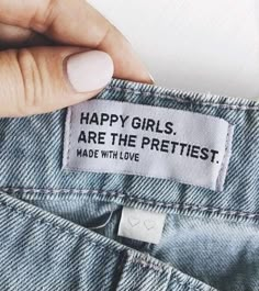 a woman's hand is holding the label on her jean pants that says, happy girls are the prettiest made with love