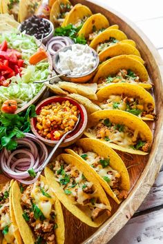 a wooden platter filled with tacos and salsa